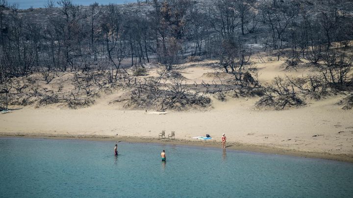 Grecia-Bañistas en una playa donde los incendios forestales destruyeron el bosque, en la parte sur de la isla griega de Rodas, el 27 de julio