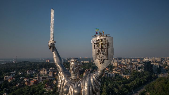 Ucrania-Los ‘Steeplejacks’ ondean la bandera ucraniana después de terminar de instalar el escudo del Monumento a la Patria de 62 metros en Kiev, el 6 de agosto, en medio de la invasión rusa de Ucrania.