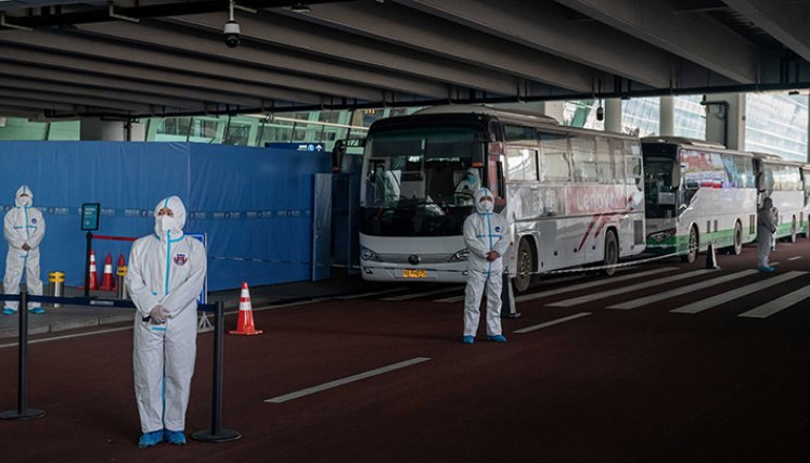 Un miembro del equipo de la Organización Mundial de la Salud (OMS) que investiga los orígenes de la pandemia Covid-19 sube a un autobús tras su llegada a una sección acordonada en el área de llegadas internacionales del aeropuerto de Wuhan/ Foto: AFP
