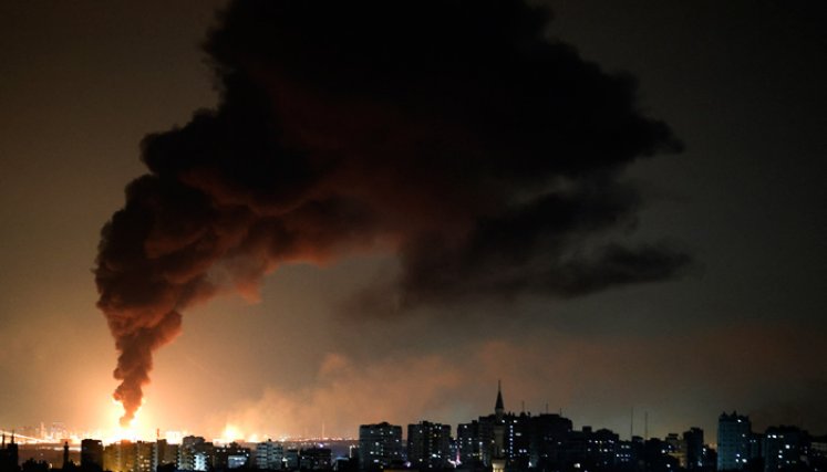 Una enorme columna de humo vista desde la ciudad de Gaza se eleva desde una instalación petrolera en la ciudad de Ashkelon, en el sur de Israel, después de que el movimiento palestino Hamas disparara cohetes desde la Franja de Gaza hacia Israel.