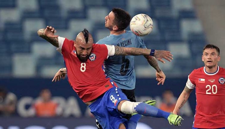 Arturo Vidal, mediocampista de Chile disputa el balón ante un defensor de Uruguay.
