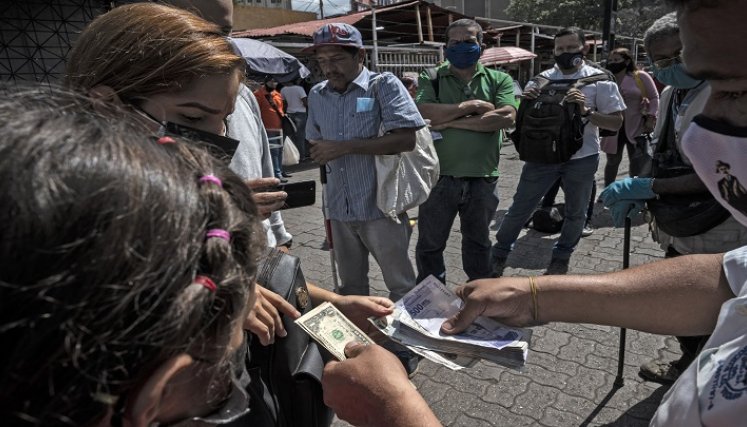 Unos comerciantes tienen máquinas para detectar billetes falsos, otros los verifican manualmente. /AFP
