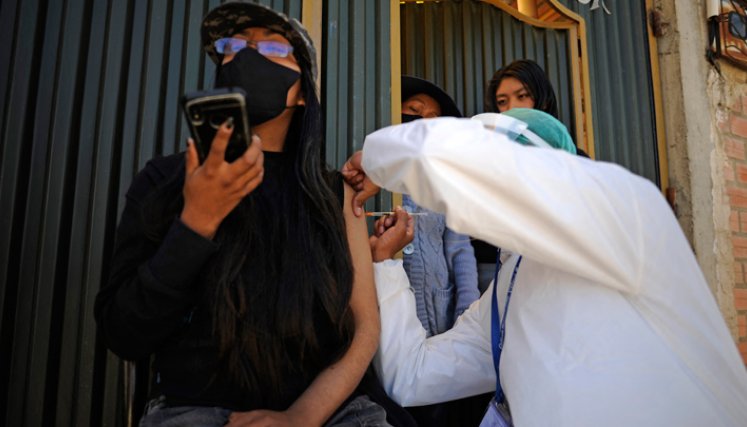 Una mujer es inoculada contra COVID-19 con la vacuna china SinoPharm por personal del Ministerio de Salud de Bolivia, afuera de su casa en el barrio Santa Rosa en El Alto, Bolivia.  / Foto: AFP
