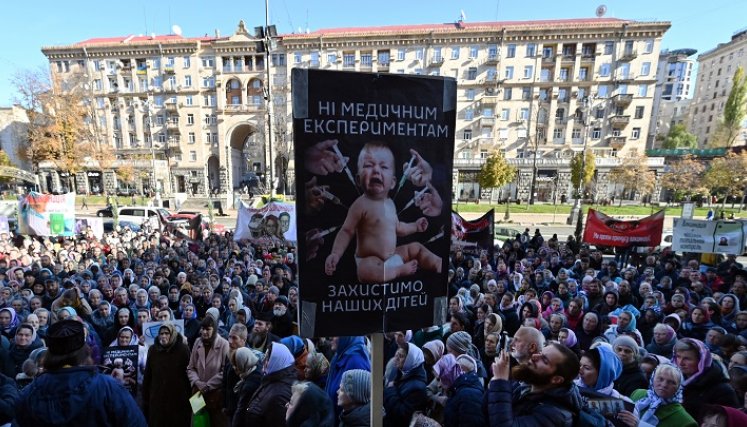 Los creyentes de la Iglesia Ortodoxa Ucraniana del Patriarcado de Moscú sostienen carteles que dicen "Sin experimentos médicos, proteja a nuestros niños" mientras realizan una manifestación frente a la oficina del alcalde. / AFP
