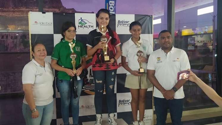  La ajedrecista Ghisell Gabriela Morales Pérez (al centro) luce el trofeo de campeona.