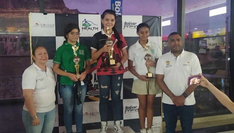  La ajedrecista Ghisell Gabriela Morales Pérez (al centro) luce el trofeo de campeona.