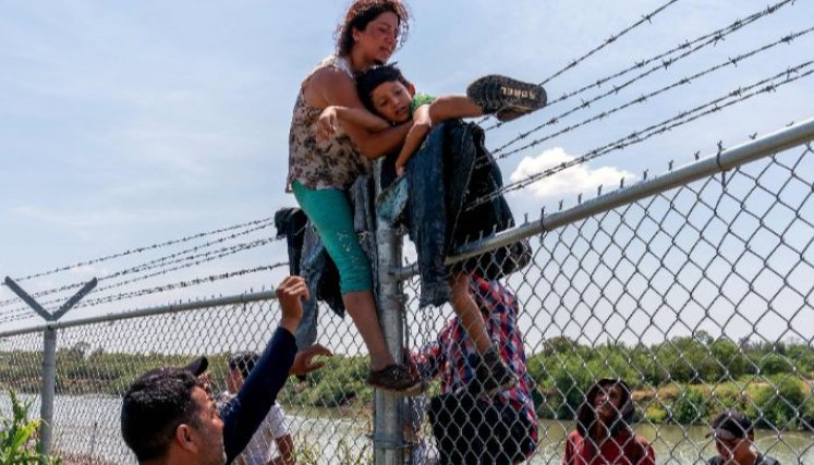 Estados Unidos-Migrantes trepan una valla de alambre de púas después de cruzar el Río Grande hacia norteamérica desde México, en Texas, el 25 de agosto.