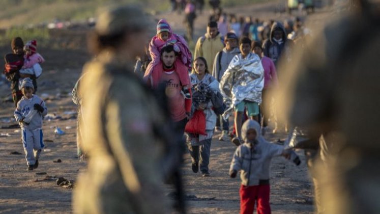 Estados Unidos-Soldados de la Guardia Nacional de Texas observan cómo miles de migrantes caminan hacia un centro de tránsito de la Patrulla Fronteriza de EE. UU. el 19 de diciembre en Eagle Pass.