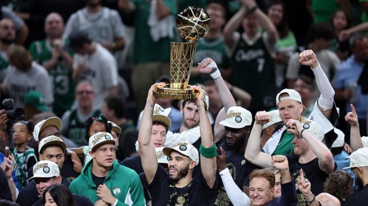 Jayson Tatum la estrella de los Celtics levanta el trofeo de campeón.